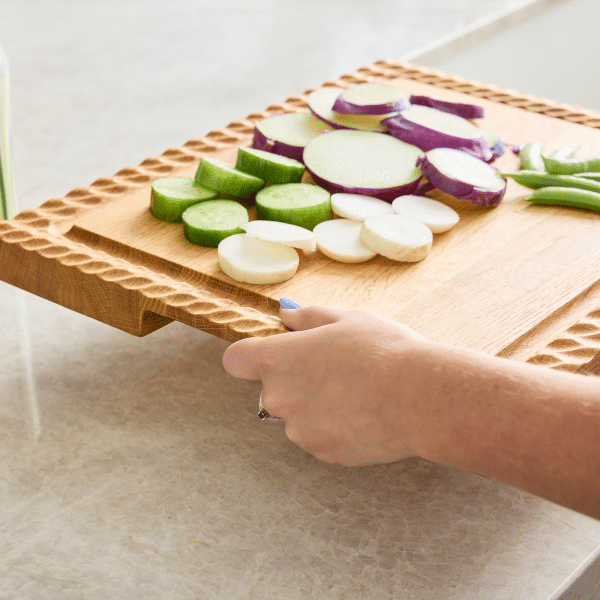 red oak wooden serving board with vegetables being held