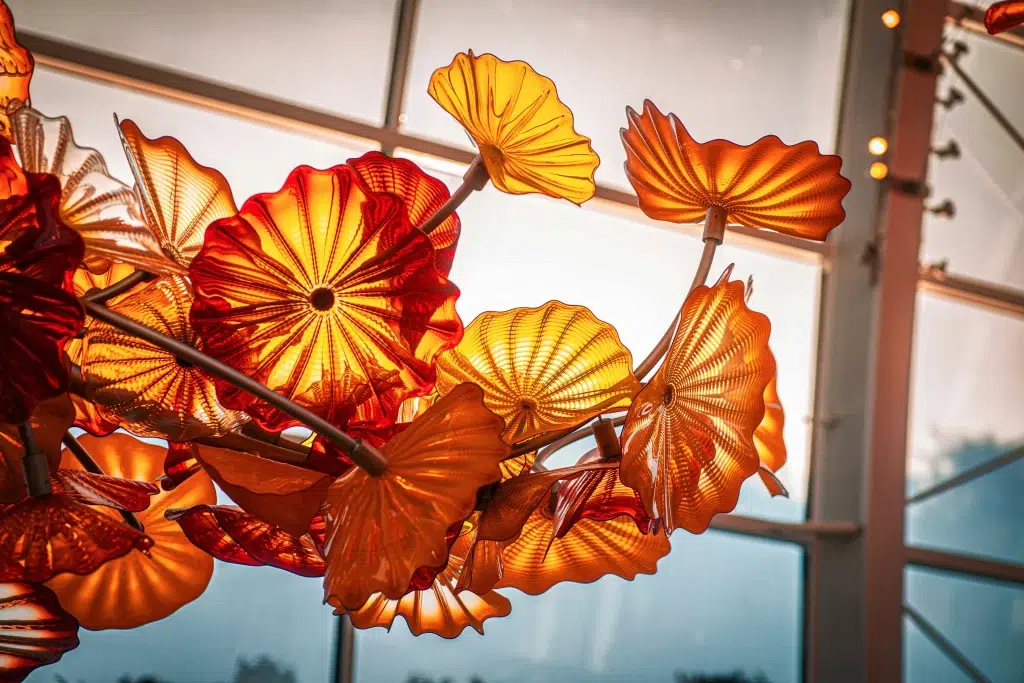 A glowing white-orange molten glass glob at the tip of a heated glassblowing rod, set against a dark background, highlighting the artistry of hand-blown glass.